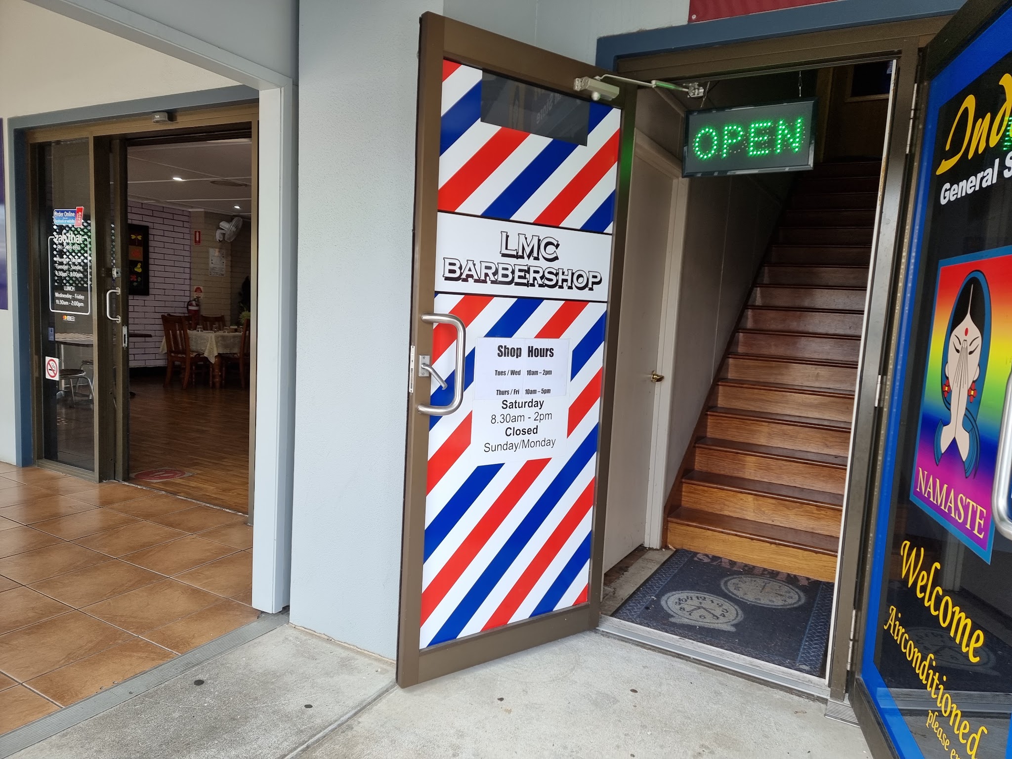 The striped LMC Barbershop door and stairs next to the general store on William Berry Drive
