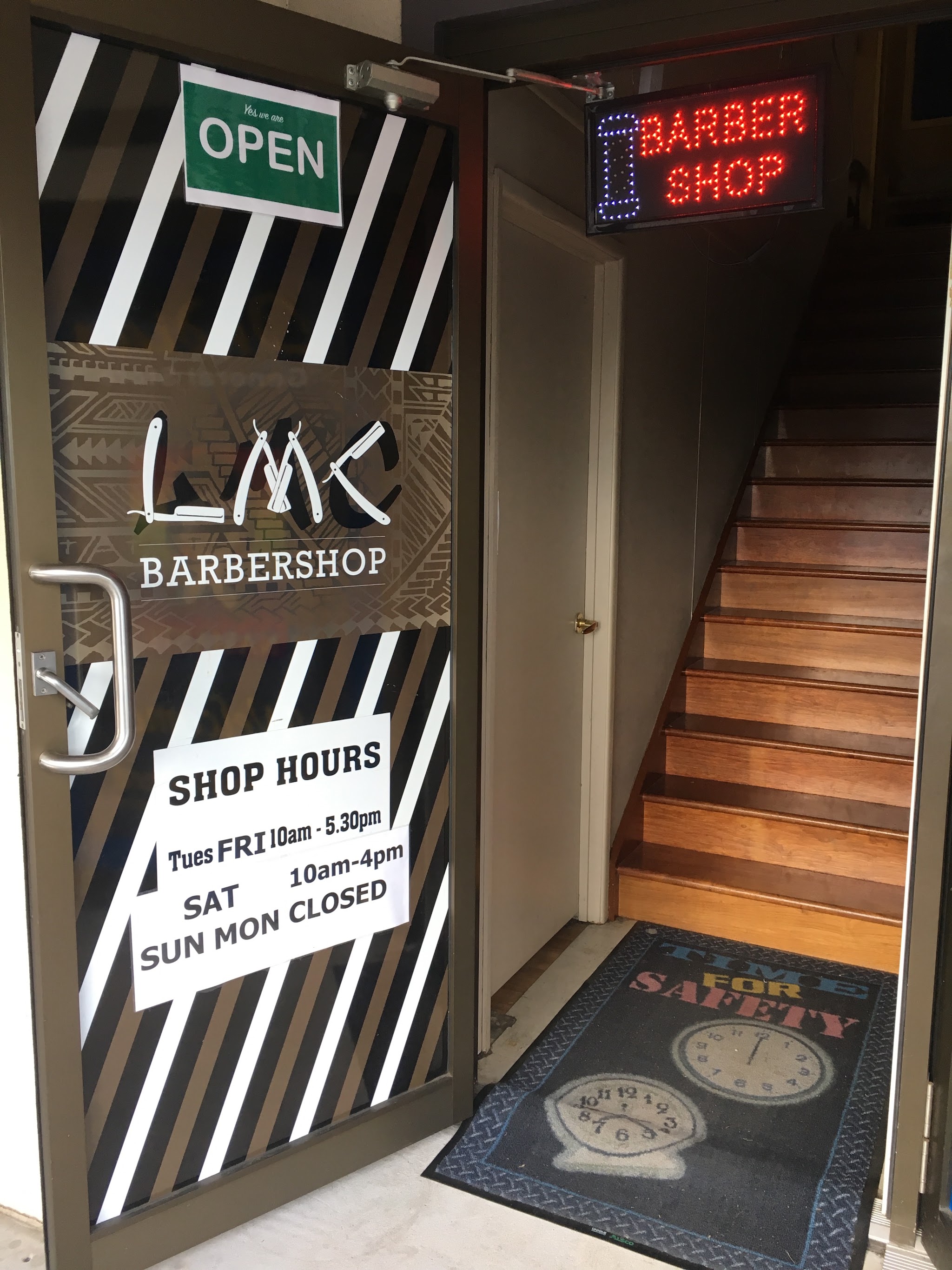 LMC Barbershop door sign with the open sign and lit barber shop sign above the stairs
